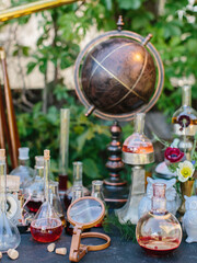 Science style party. In the foreground are flasks and vials with cocktails. Vintage leather globe.