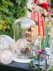 Vintage decor. Cloche glass cap with roses and peonies, glass balls, glass boxes with flowers, red candles in gold candlesticks.