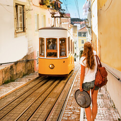 Traveler woman waiting yellow traditional tram on a street in Lisbon- Portugal - obrazy, fototapety, plakaty