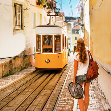 Traveler woman waiting yellow traditional tram on a street in Lisbon- Portugal