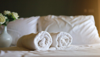 White towel roll on a white pillow and bed decoration in bedroom interior to vintage style hotel. vacation concept.