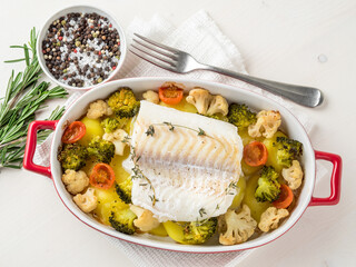Fish cod baked in the oven with vegetables - healthy diet healthy food. Light white wooden...