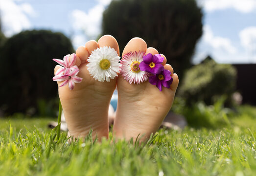 child's bare feet lie on bright juicy green grass. flowers of daisies between toes. joy, cheerful positive atmosphere, carelessness, happy childhood. hello summer holidays. Flower surprise with love
