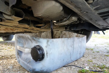 Black used oil drained from the car's engine. Draining old car oil. Oil changing in the car. Car oil change.