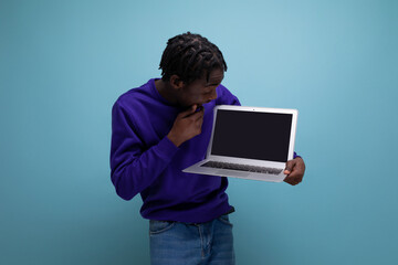 well-groomed dark-skinned European young brunette man with dreadlocks with a laptop