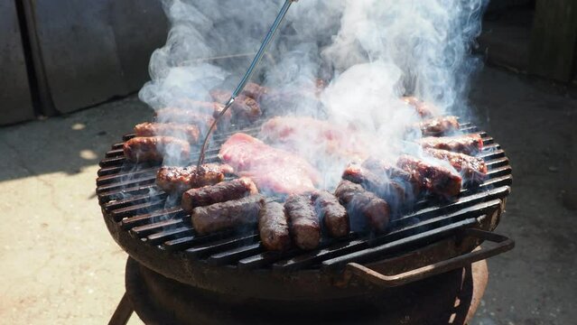 Cevapi, cevapcici is a grilled dish of minced meat found traditionally in the countries of southeast Europe and Balkans. Turkish kebap. The grill master turns the meat in thick smoke.