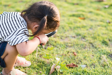 The little  girl looked down at the grass. Explore ants with a magnifying glass,children explore nature curious future botanist.