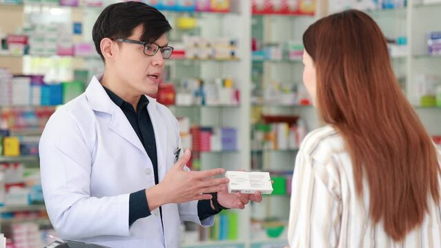 Asian man Pharmacists provide consultation and explain the use of medication to patients who purchase medication at the pharmacy. Shelves with drug and Health Care product