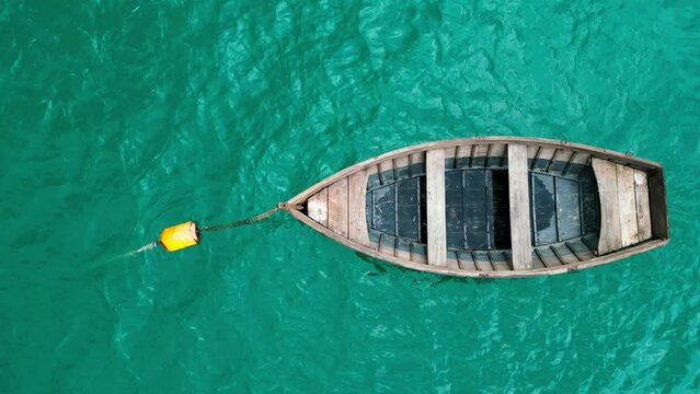 A breathtaking top view of a serene blue-green lake with a wooden boat gently floating on its surface.