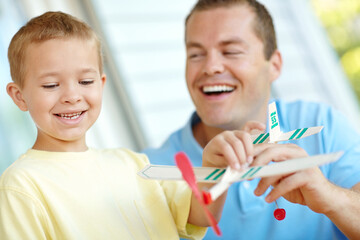 Obraz premium Like this, dad. Young father playing with a model airplane with his son at home.