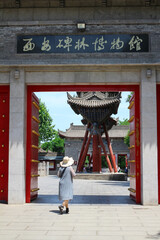 XI'AN. CHINA.A woman in a hat passes through the red gate leading to the Cathedral mosque in XI'an. Old town. Xian. China.