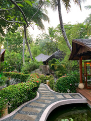 A day in the Maldives, shaped roads paved with stones and tiles between trimmed bushes, palm trees and wooden buildings