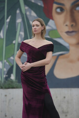 Outdoor portrait of woman in purple velvet long elegant dress in the city, fall fashion collection