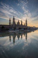 Fototapeta premium del Pilar basilica, one of the important architectural symbols of zaragoza, and the Ebro river and its reflection with sunset colors and clouds