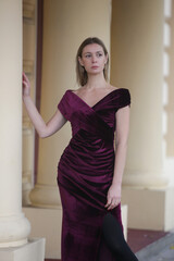 Outdoor portrait of woman in purple velvet long elegant dress in the city, fall fashion collection