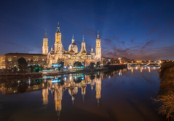 Fototapeta na wymiar del Pilar basilica, one of the important architectural symbols of zaragoza, and the Ebro river and its reflection with sunset colors and clouds