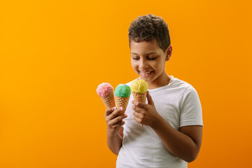 The child holds three portions of ice cream in waffle cones and enjoys different flavors of cool ice cream.