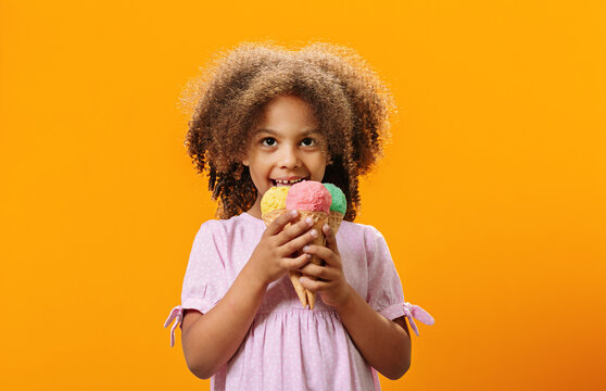 Portrait of a happy pretty Black girl eating yummy ice cream in summer.
