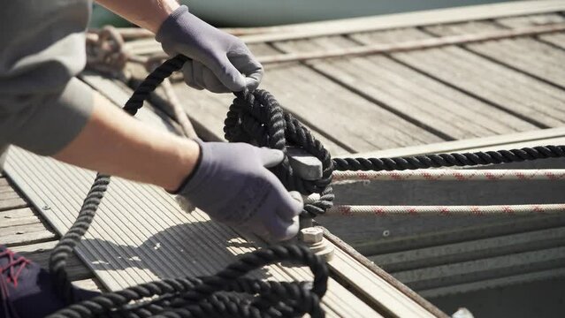 A man wearing gloves ties a strong cleat hitch. Knot for cleat dock. Close-up. Mooring knot. Sailor. Sailing boat.Sailboat mooring. 4K