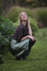 Outdoor portrait of woman in green silk satin skirt and brown blouse in the park during autumn...