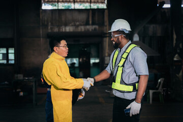 Engineer or foreman are happy and shake hands in industrial manufacturing factory.