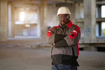 African american worker stands at construction area and looks at camera