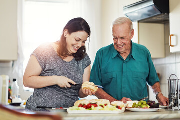 Its an honor to care for aging parents. a woman making her senior male parent a sandwich.