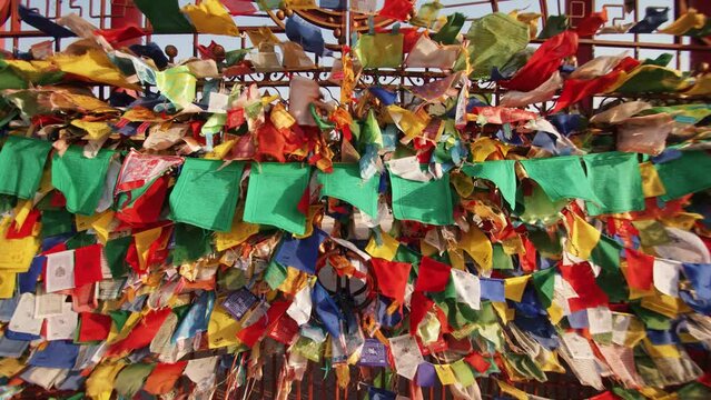 Colored ribbons and small flags with prayer flutter in wind on gates adorned with buddhist symbols