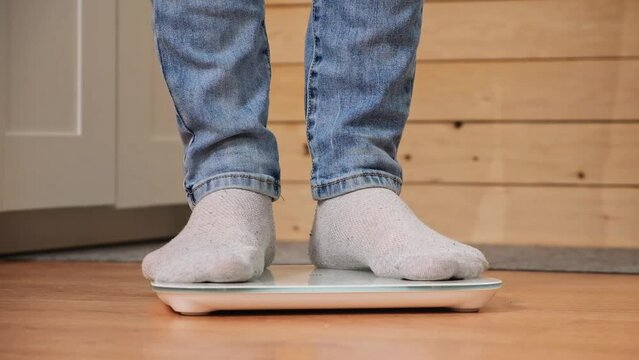 A man stands on the scales. The guy is weighing himself. Floor scales for health. Weight control.