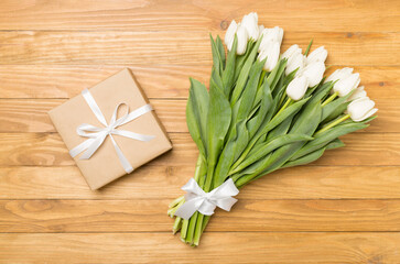 White tulip bouquet and gift box on wooden background, top view