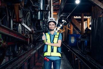 Portrait of woman engineer standing and looking camera in train factory. Maintenance cycle concept.