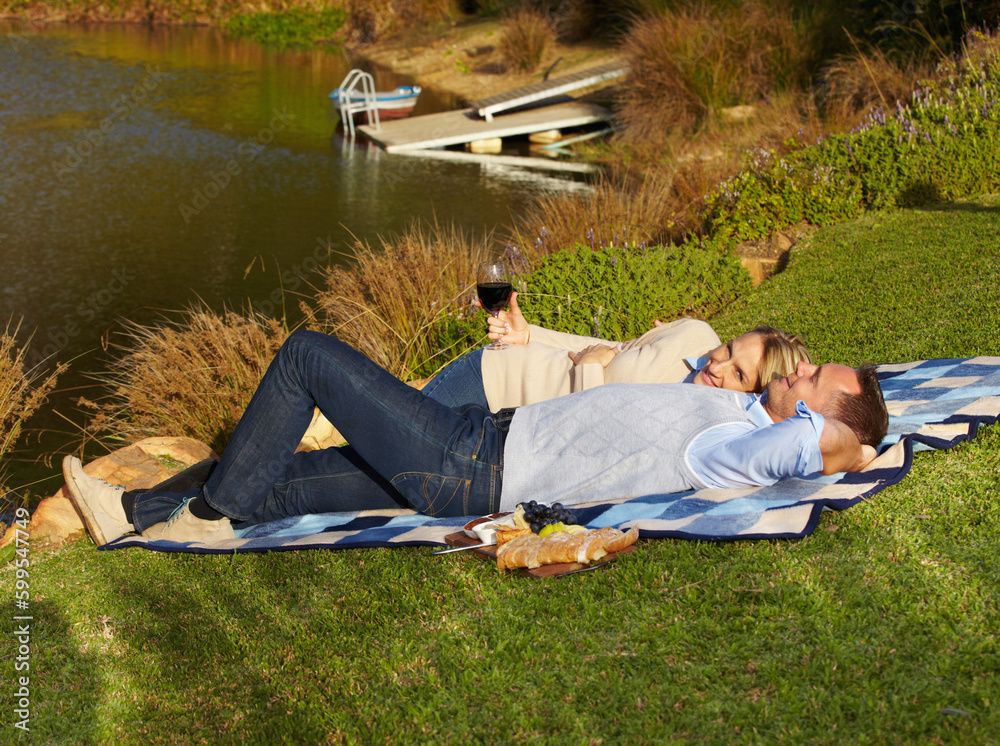 Sticker Couple, picnic and lying by lake with wine outdoor, having fun and bonding on vacation. Portrait, alcohol and man and woman by river to relax, happiness and enjoying romantic time together in summer.