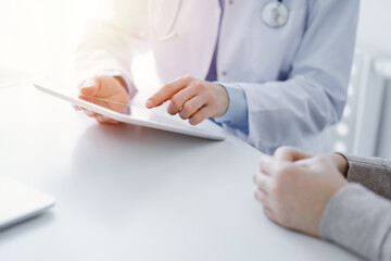 Doctor and patient discussing current health questions while sitting at the table in clinic office, only hands closeup. Medicine concept