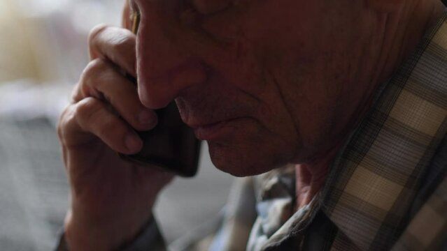 close-up of the face of a caucasian old man talking on the phone, selective focus.real pensioner. old people lifestyle. elderly man with phone