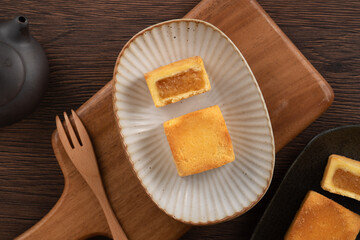 Delicious pineapple cake pastry in a plate on wooden table background with tea.