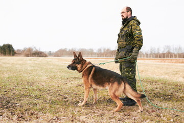 Male officer, military uniform and german shepherd on leash or dog guarding territory and outdoors....