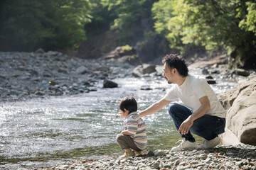 川で遊ぶ兄弟とパパの夏休みの家族旅行のレジャーやアウトドア、キャンプのイメージ