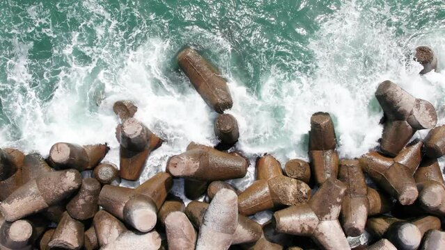 Top down view of waves crushing the coast line, concrete tetrapods.