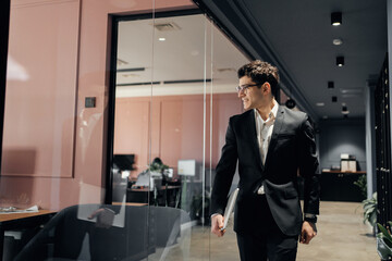 Career of an office director a young successful man walks down the corridor, alone in a coworking space, works in formal attire.