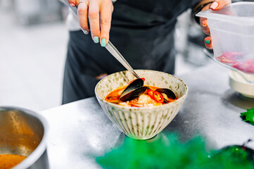 woman chef cooking seafood soup on restaurant kitchen