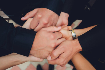 two man and three women holding hands on a table implying a polyamory relationship or love triangle.