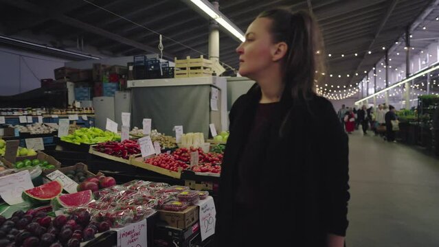 A woman in an indoor market looks at the fruit on offer.