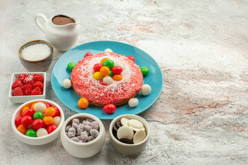 front view delicious cream cakes with colored candies on light white background cookie candy cake color rainbow