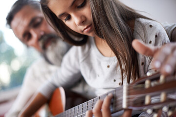 Girl learning to play guitar, grandfather teaching child with music education and help with...