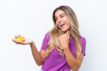 Young pretty Uruguayan woman holding a tartlet isolated on white background celebrating a victory