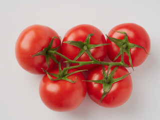 A bouquet of fresh red tomatoes with green stems isolated on a white background. The outline of the crop.