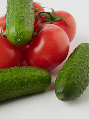 Cucumber and tomato close-up on a white isolated background. Natural ripe vegetables, organic tomato and cucumber top view