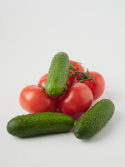 Cucumber and tomato close-up on a white isolated background. Natural ripe vegetables, organic tomato and cucumber top view