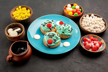 front view little creamy cakes with candies on a dark grey background dessert cake biscuit candy cookie color