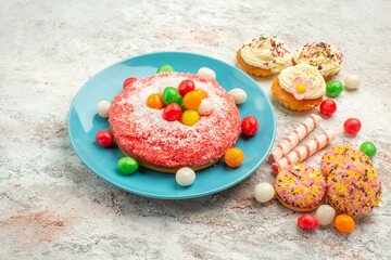 front view pink cake with colorful candies and cookies on white background goodie rainbow candy dessert color cake